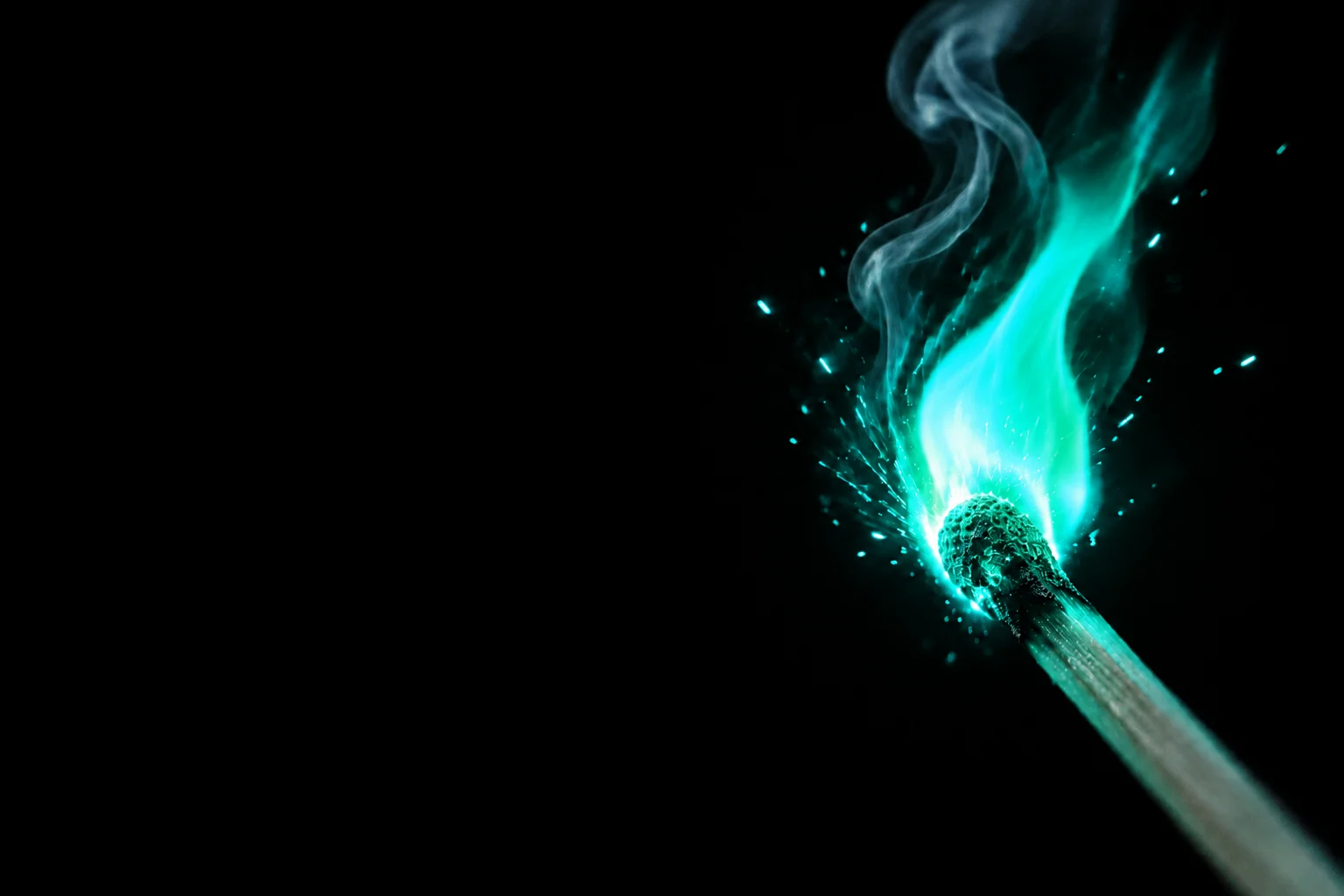 A single lit match burning with a teal copper flame against black