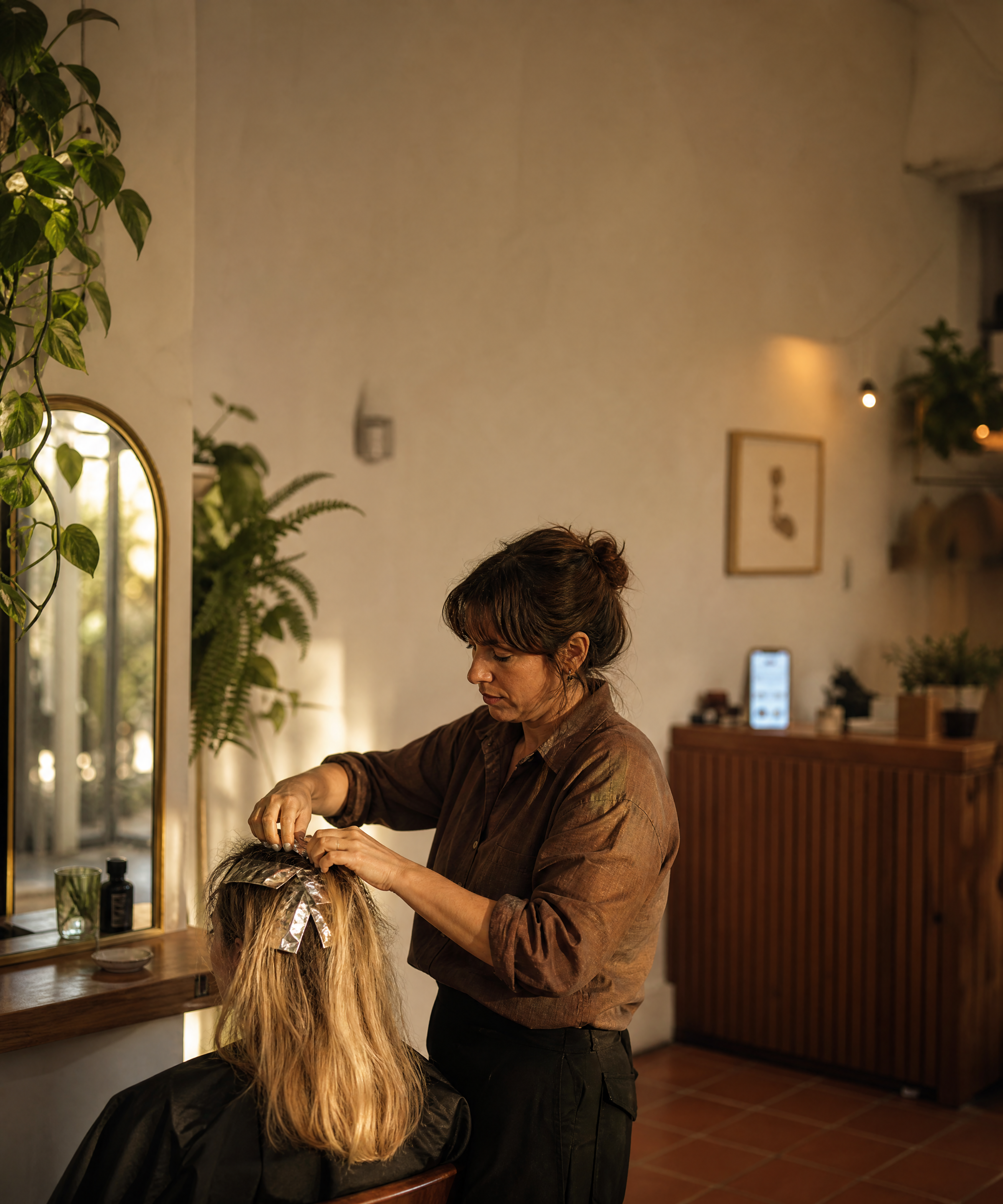 A barber mid-cut while Lily answers the shop phone